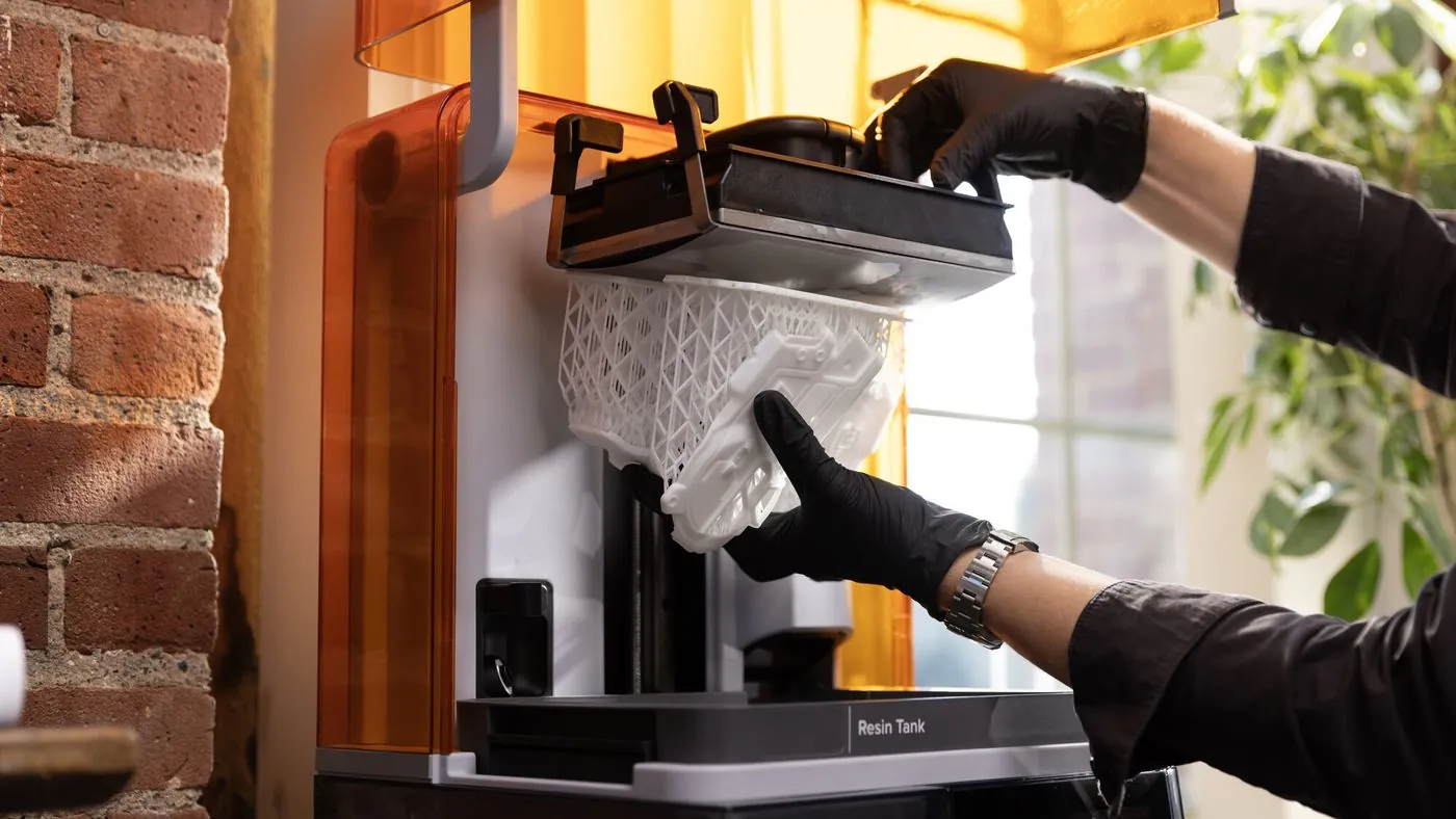 Manos con guantes retirando una pieza de la Build Platform Flex